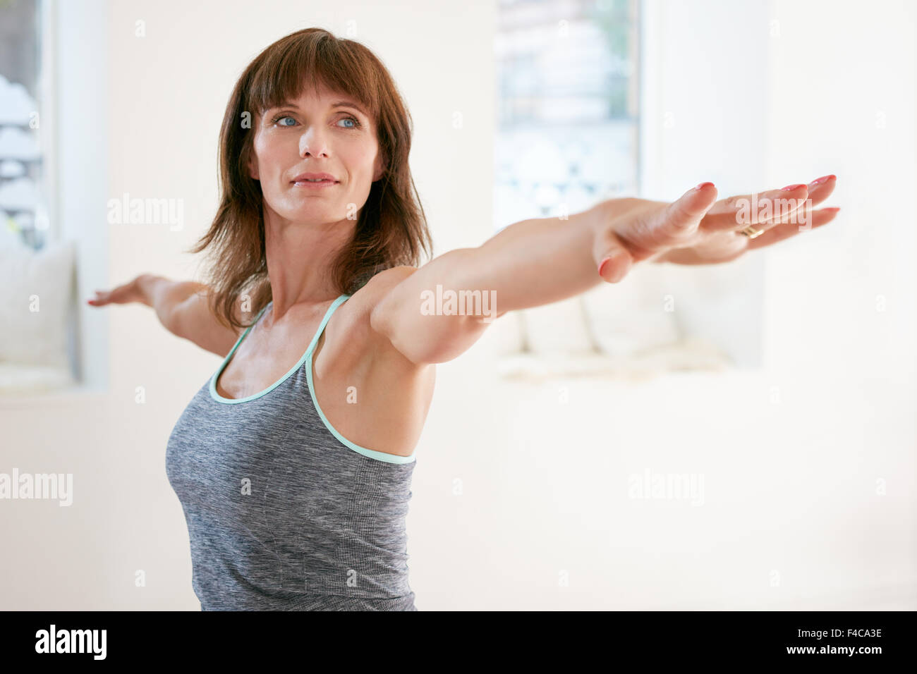 Portrait of young woman stretching her arms et à la voiture à la salle de sport. Belle femme en yoga warrior pose, Virabhadr Banque D'Images