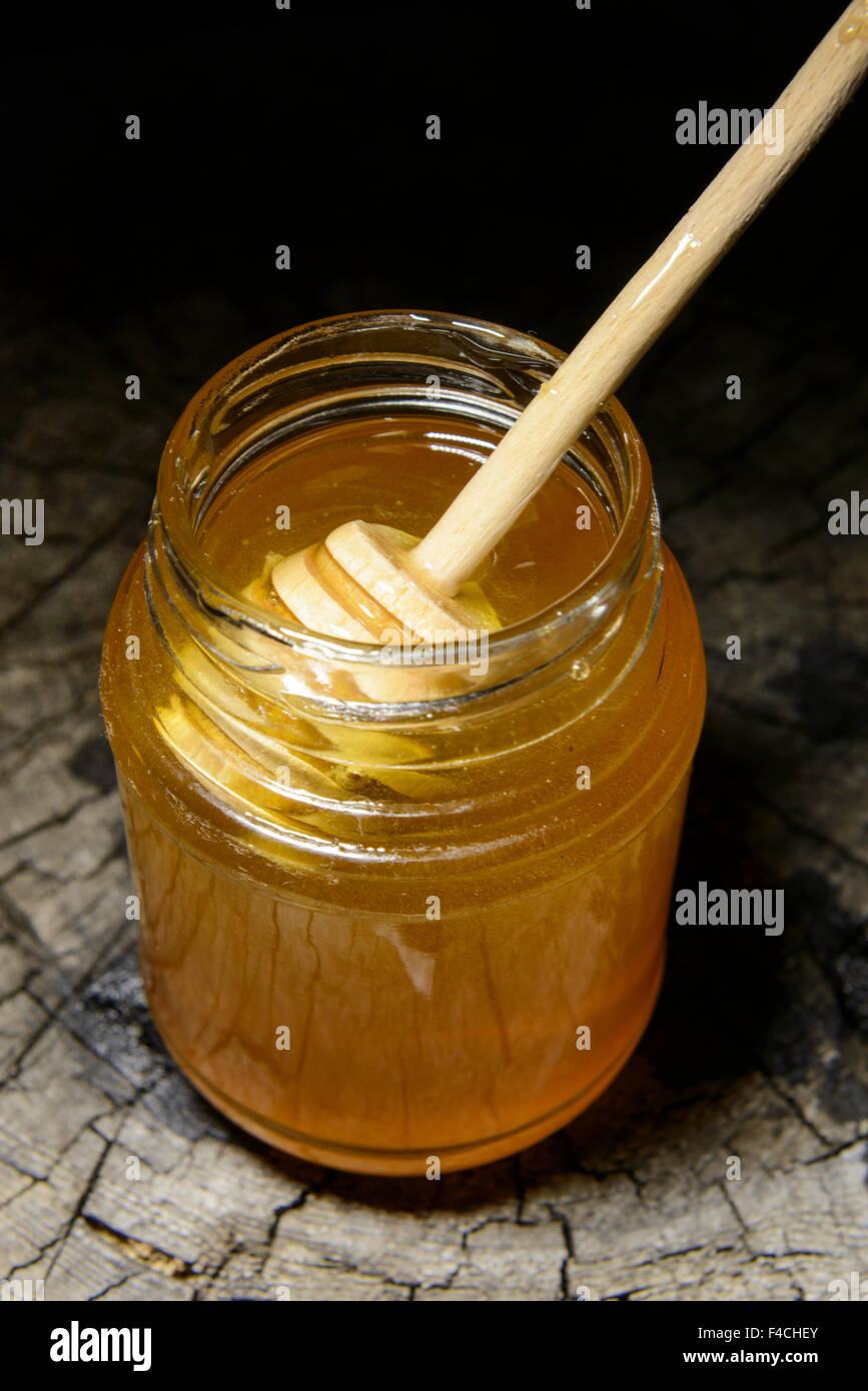 Pot de miel et bâton à miel sur un fond de bois Banque D'Images