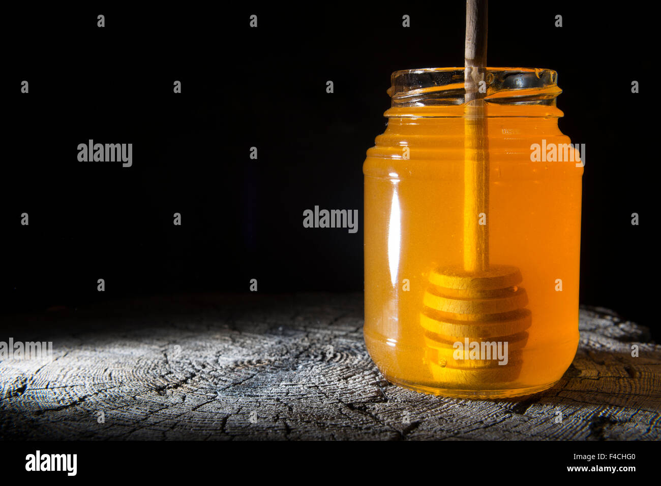 Pot de miel et bâton à miel sur un fond de bois Banque D'Images