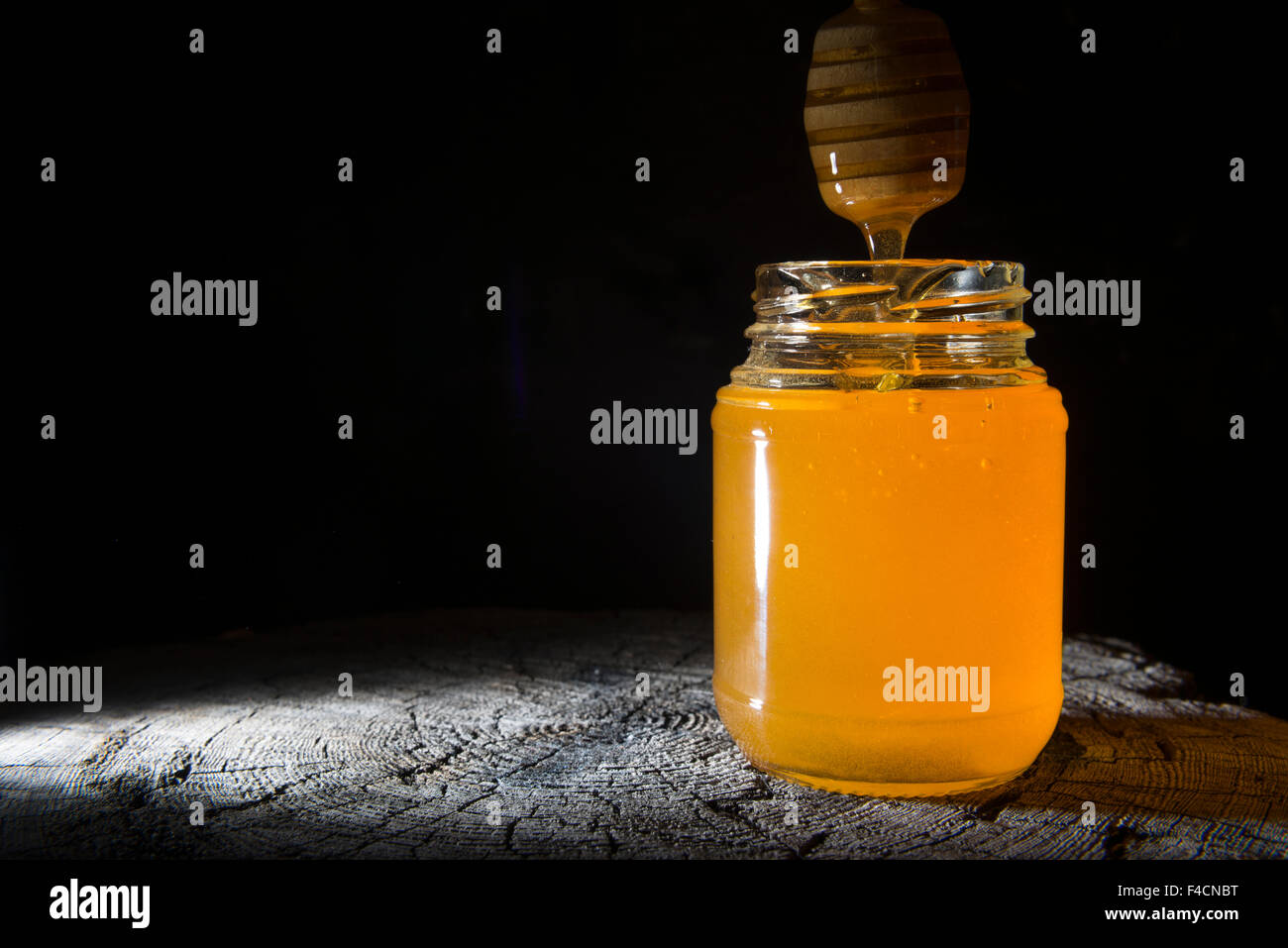 Pot de miel et bâton à miel sur un fond de bois Banque D'Images