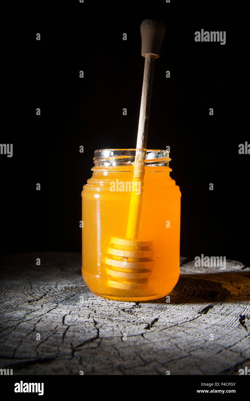 Pot de miel et bâton à miel sur un fond de bois Banque D'Images