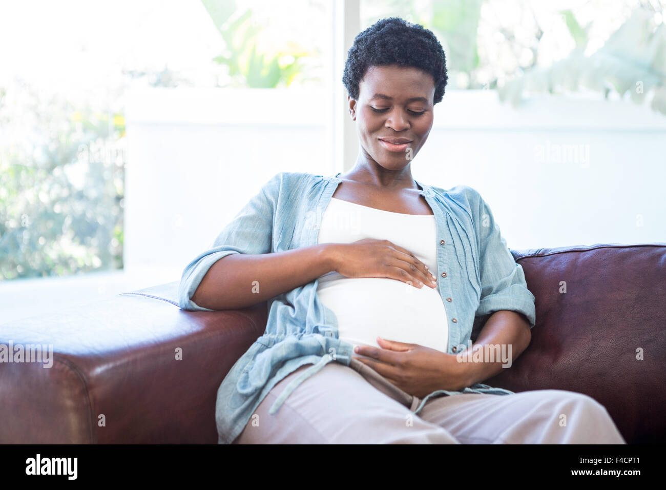 Smiling pregnant woman sitting on the couch Banque D'Images
