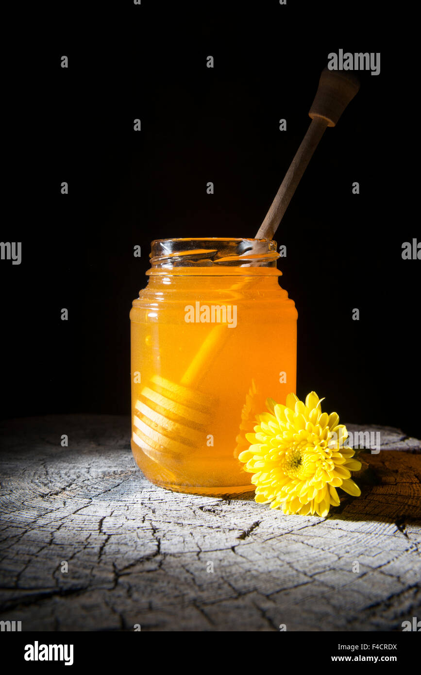 Pot de miel et bâton à miel sur un fond de bois Banque D'Images