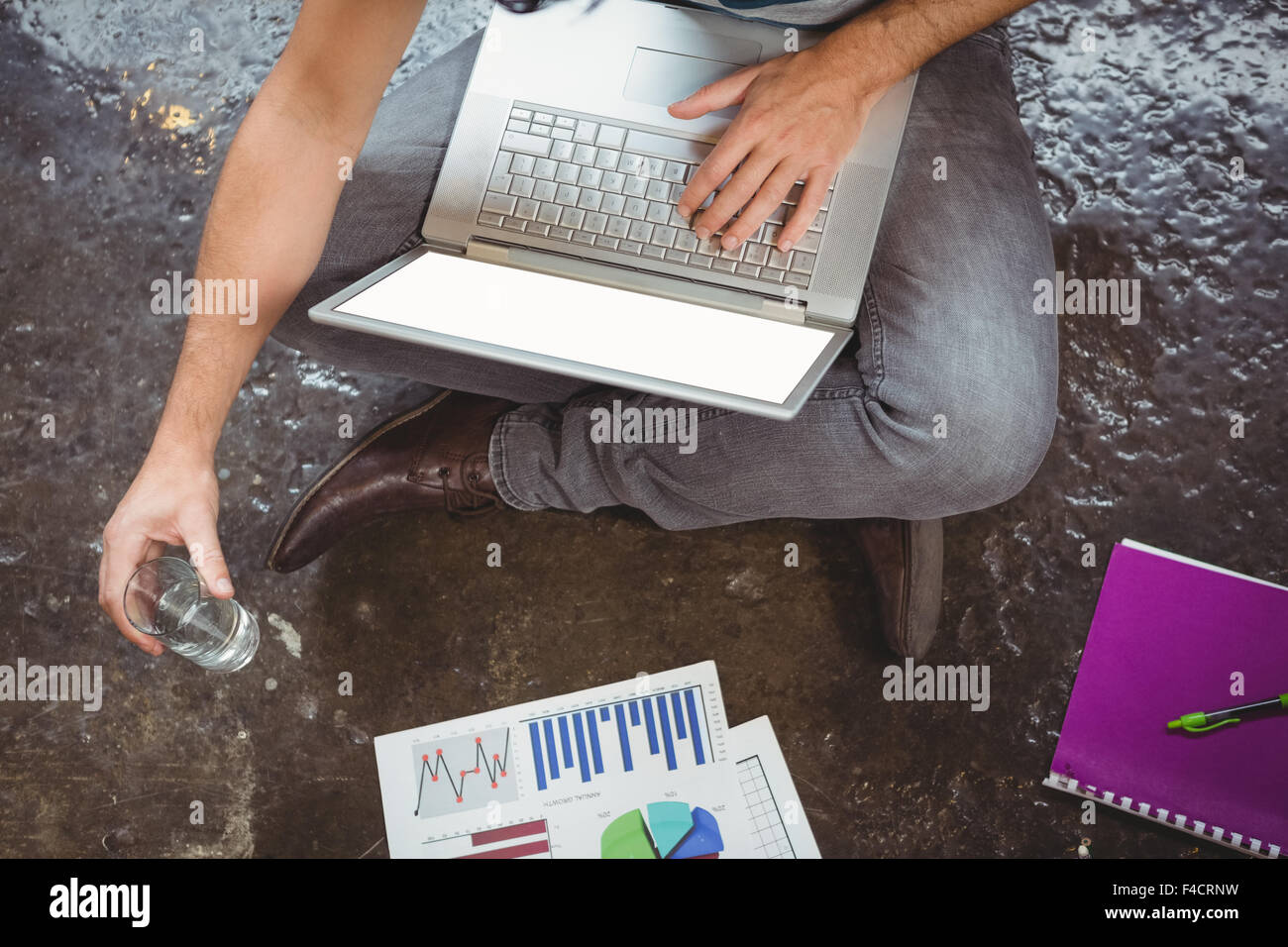 La section basse de businessman using laptop while holding drinking glass Banque D'Images