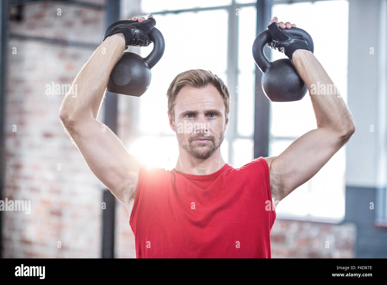 L'accent musculaire man lifting kettlebells Banque D'Images