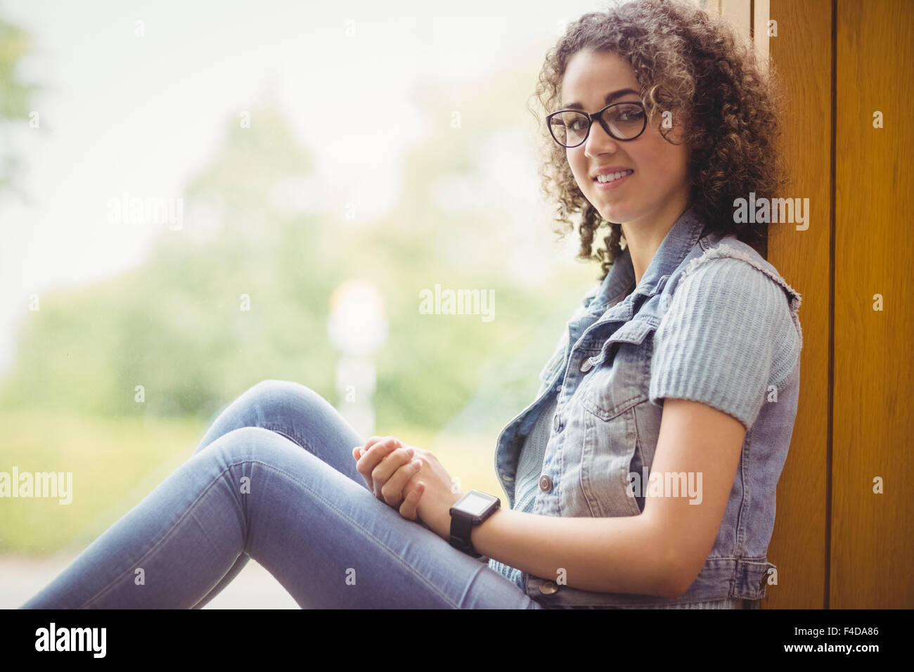 Pretty student sitting by window smiling at camera Banque D'Images