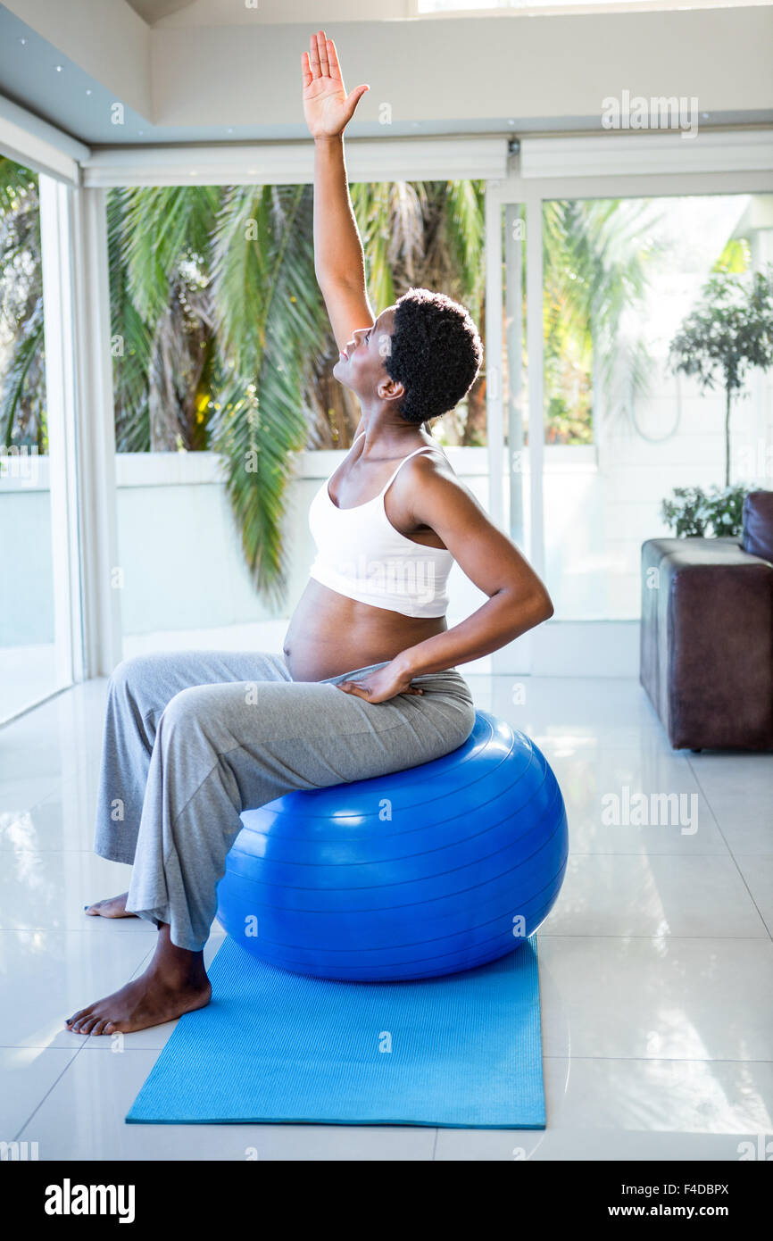 Femme enceinte l'étirement en position assise sur boule d'exercice Banque D'Images
