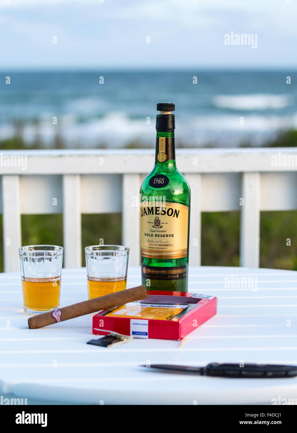Bouteille de whisky Jameson et des cigares cubains sur la table sur le pont de beach house à Emerald Isle, Caroline du Nord. Banque D'Images