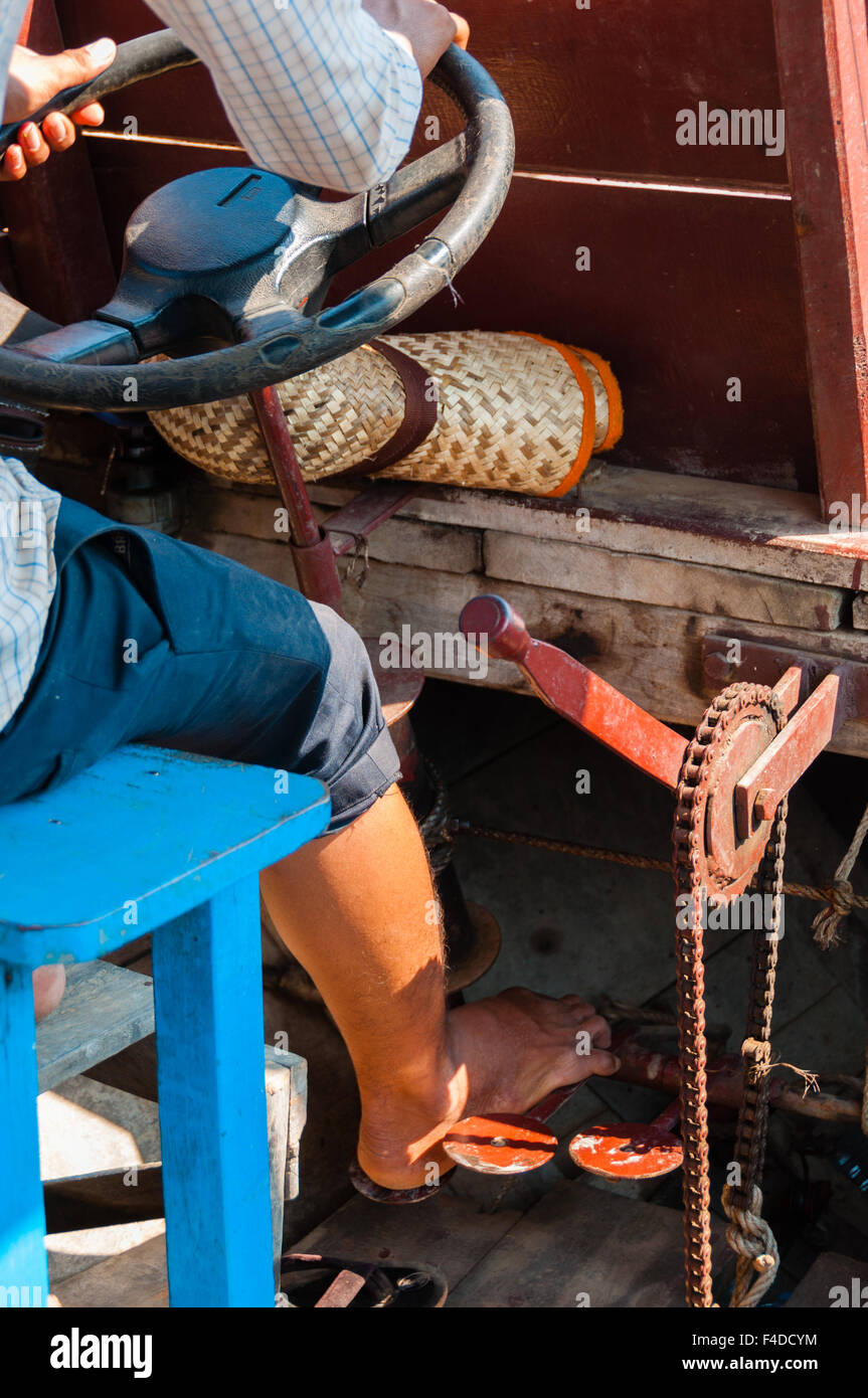 Asian boy driving boat on river Banque D'Images