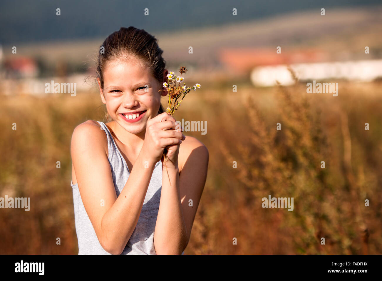 Belle, jeune fille de 11 ans dans le domaine, smiling, quelques fleurs Banque D'Images