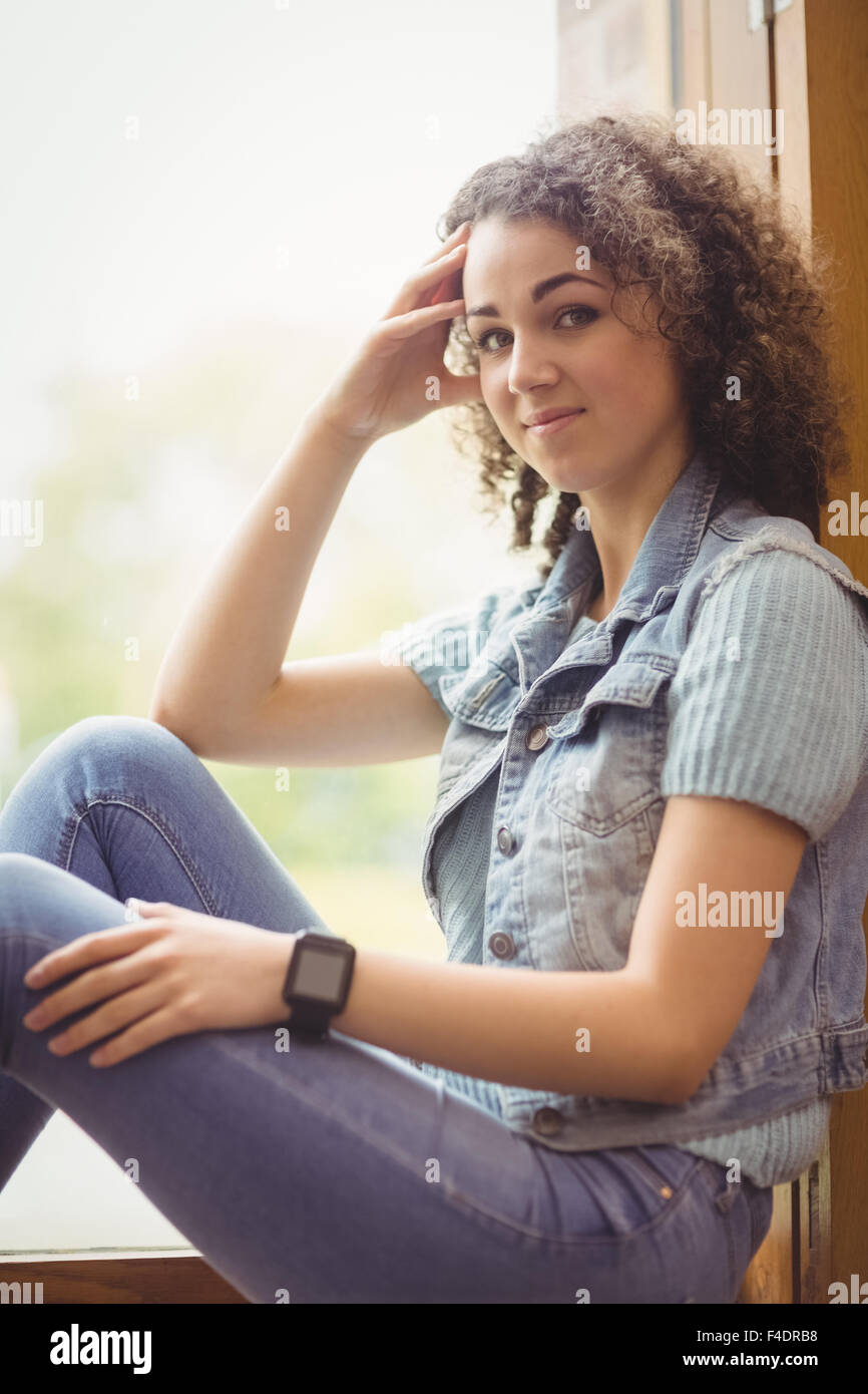 Pretty student sitting by window smiling at camera Banque D'Images