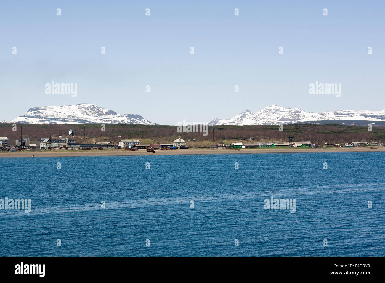 La Russie, Kamchatka, Ossora, vue de la ville et les montagnes enneigées au-dessus de la mer Banque D'Images