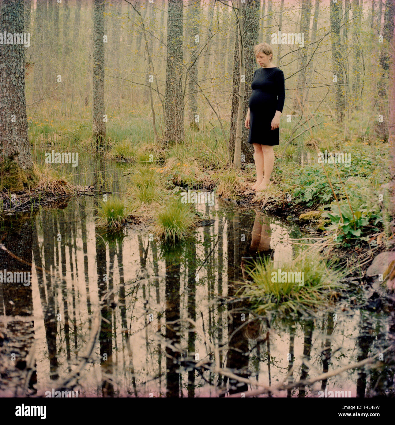 Femme debout près d'un petit lac, Sodermanland, Suède. Banque D'Images
