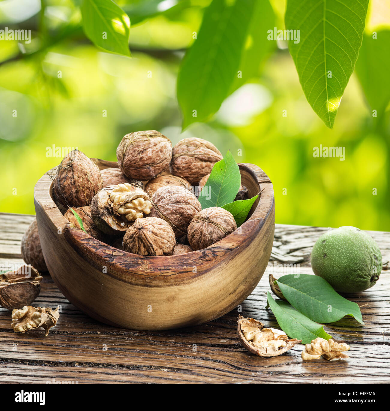 Les noix dans le bol en bois sur la table sous le noyer. Banque D'Images