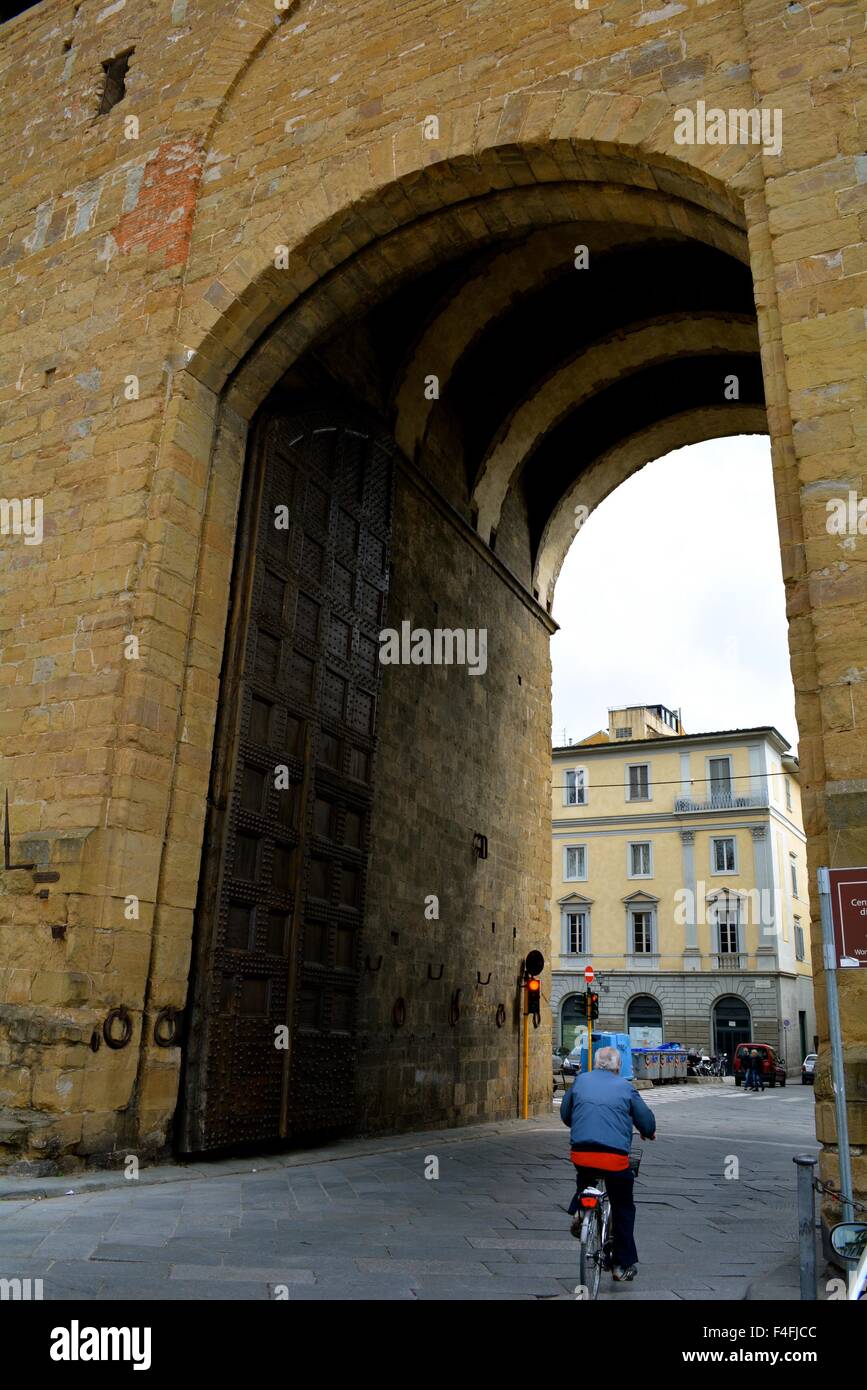 Vélo homme au travers du portail des anciens murs de la ville de Florence Italie Banque D'Images