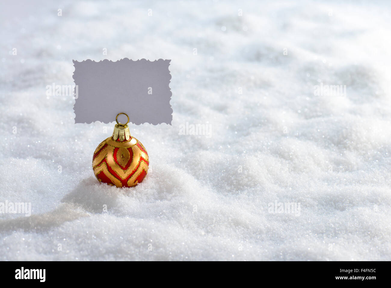 Boule de Noël avec carte de souhaits sur la neige vierge Banque D'Images