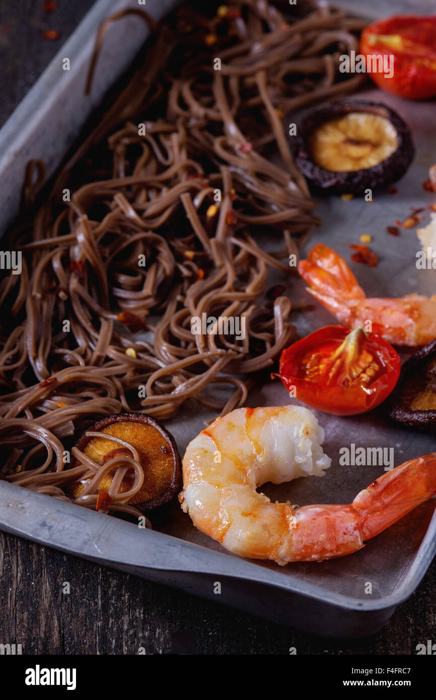 Dîner de style asiatique avec des nouilles soba, des champignons shiitake, des tomates grillées et les crevettes dans un plat de cuisson en aluminium plus ancienne en bois b Banque D'Images