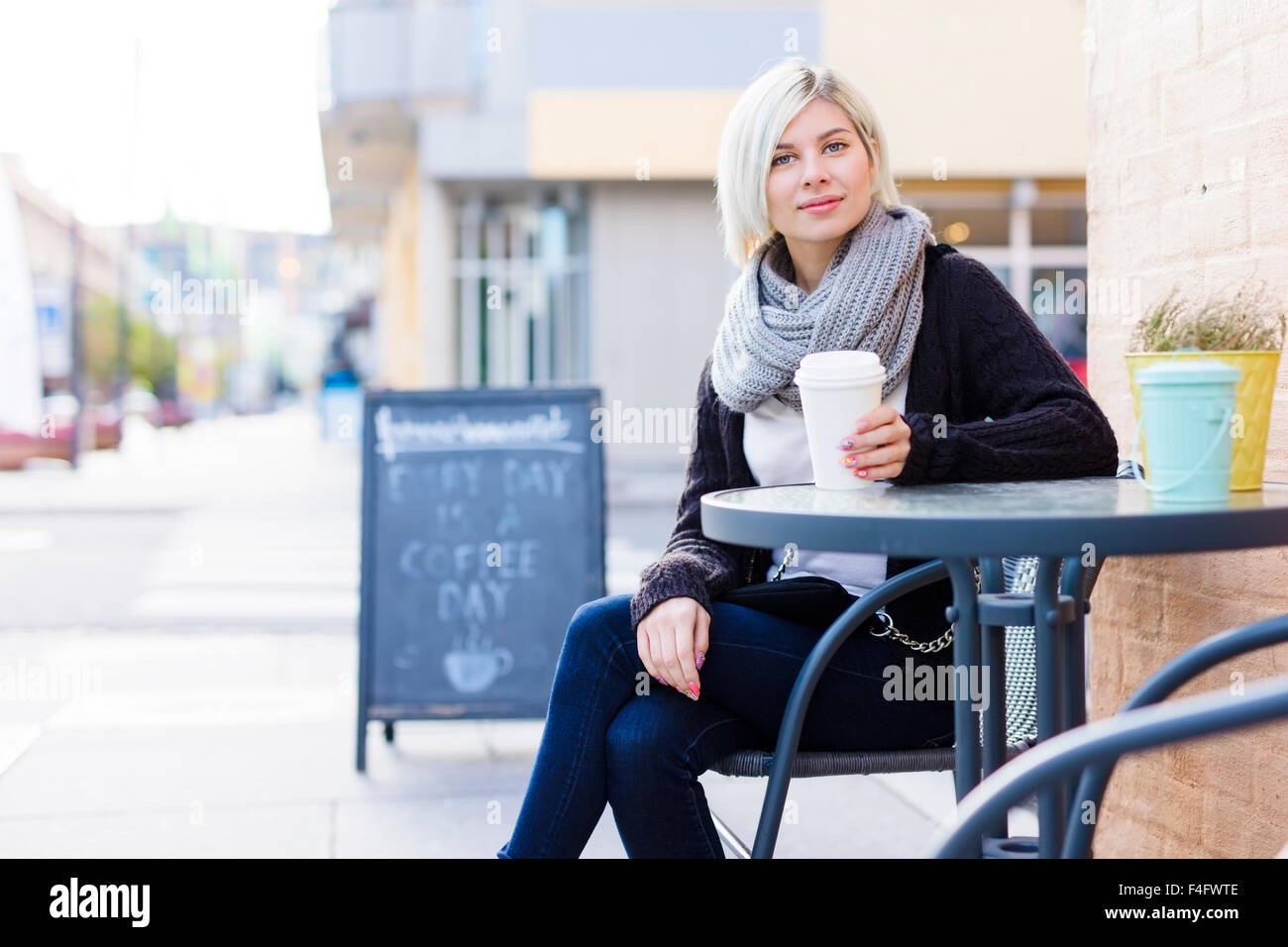 Smiling blonde woman drinking coffee at outdoor cafe Banque D'Images