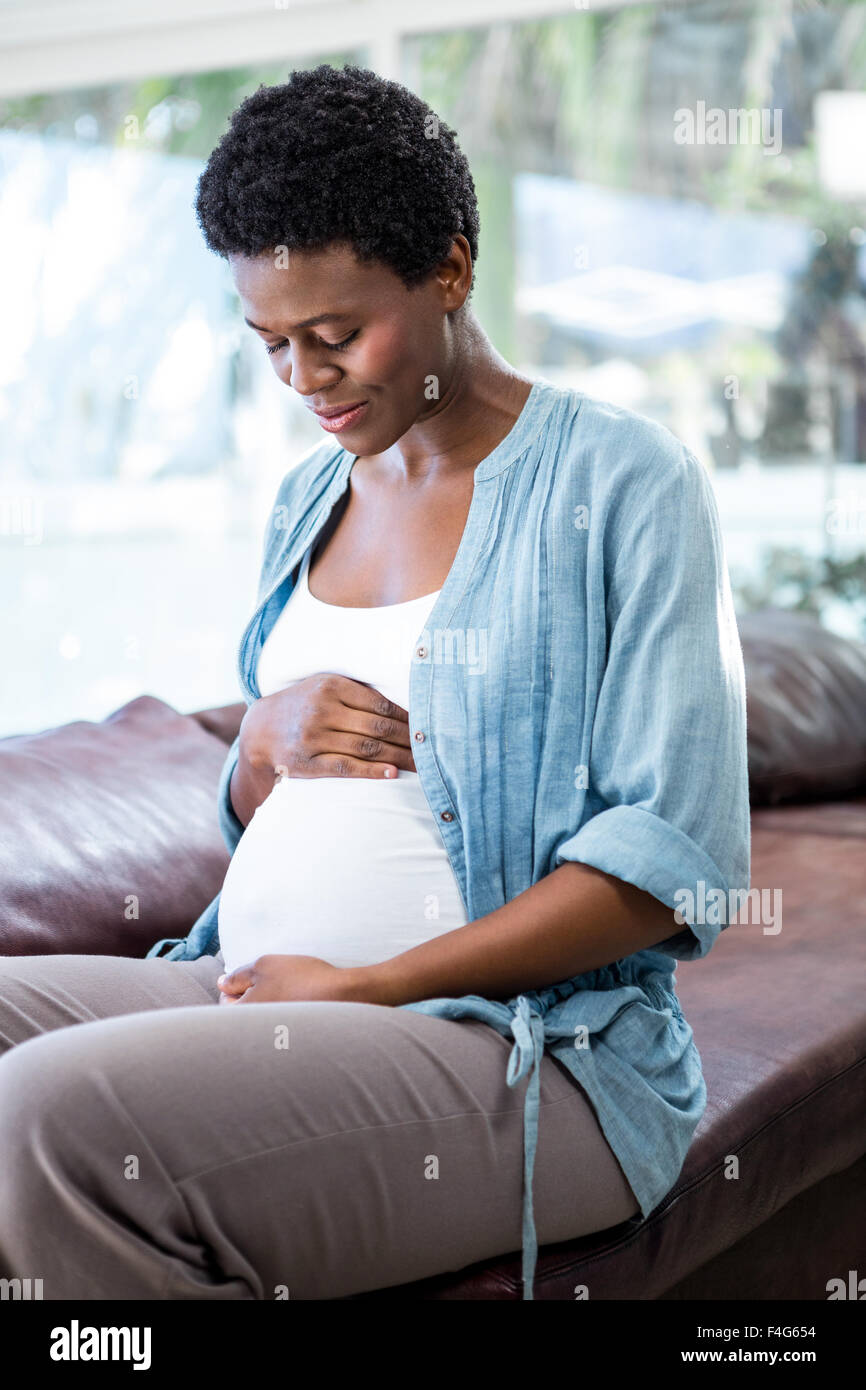 Smiling pregnant woman sitting on the couch Banque D'Images