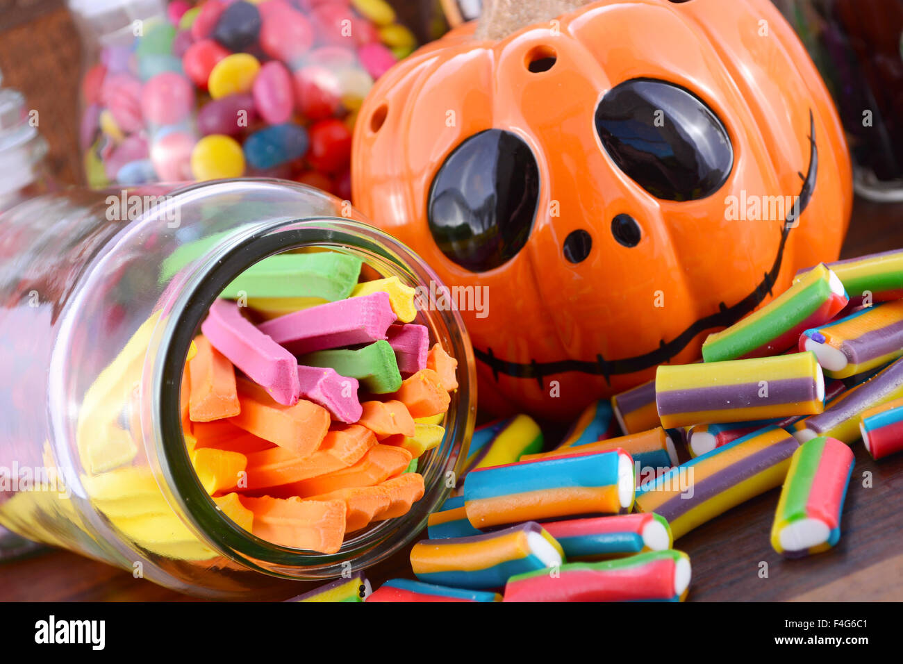 Happy Halloween Candy dans des bocaux d'Apothicaire en verre avec orange citrouille Jack O Lantern libre sur la table en bois sombre. Banque D'Images