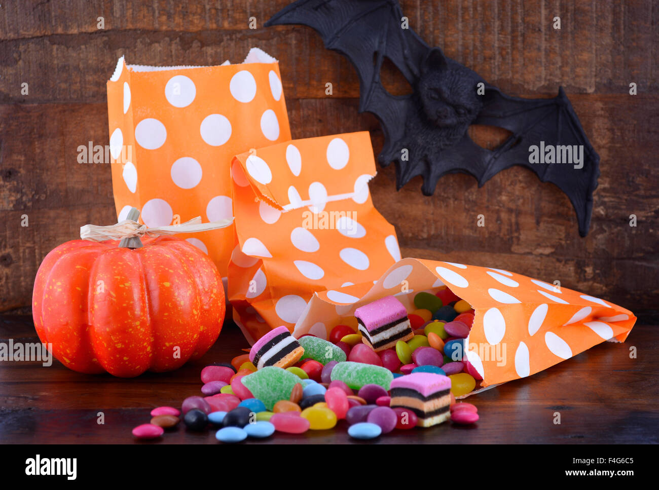 Bonbons Halloween Trick ou traiter avec des sacs de bonbons colorés, la citrouille et bat sur fond de table en bois sombre. Banque D'Images