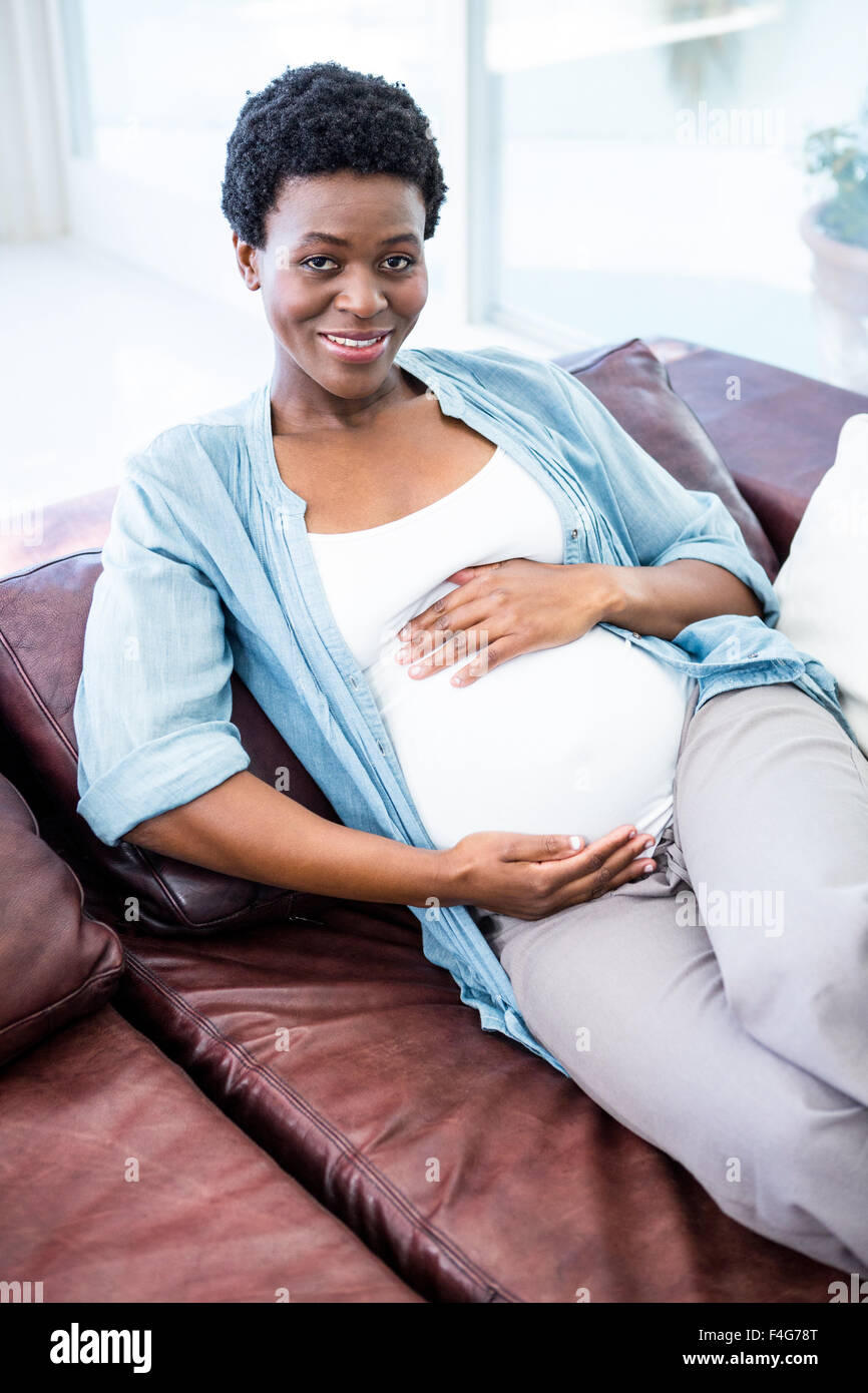 Smiling pregnant woman sitting on the couch Banque D'Images