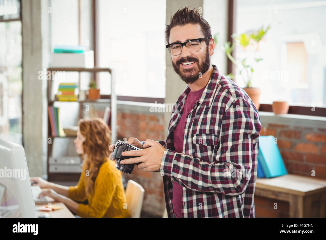 Smiling man holding camera at office Banque D'Images