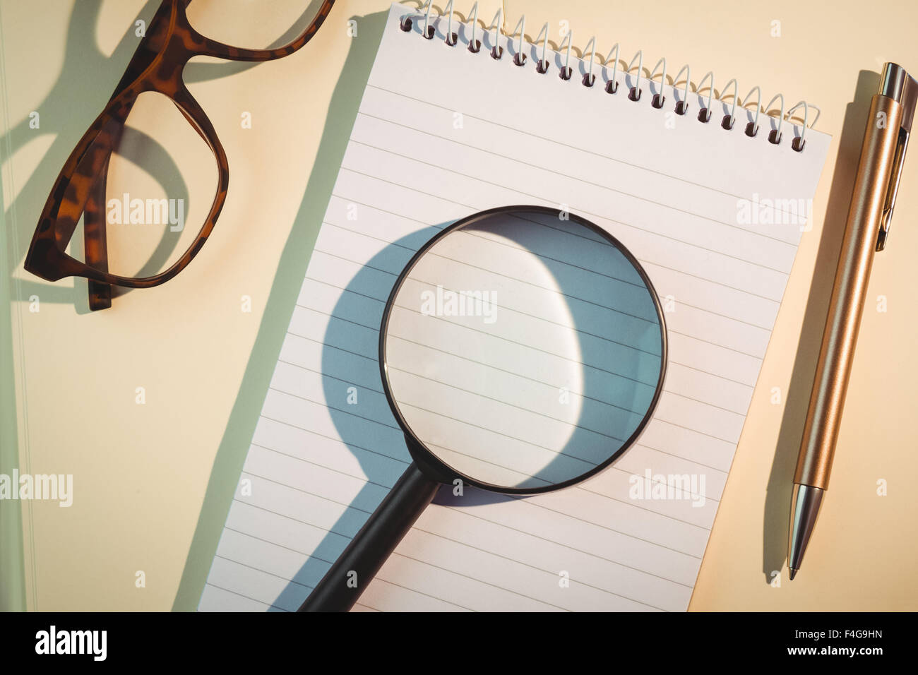 Loupe sur le bloc-notes et stylo au milieu de lunettes Banque D'Images