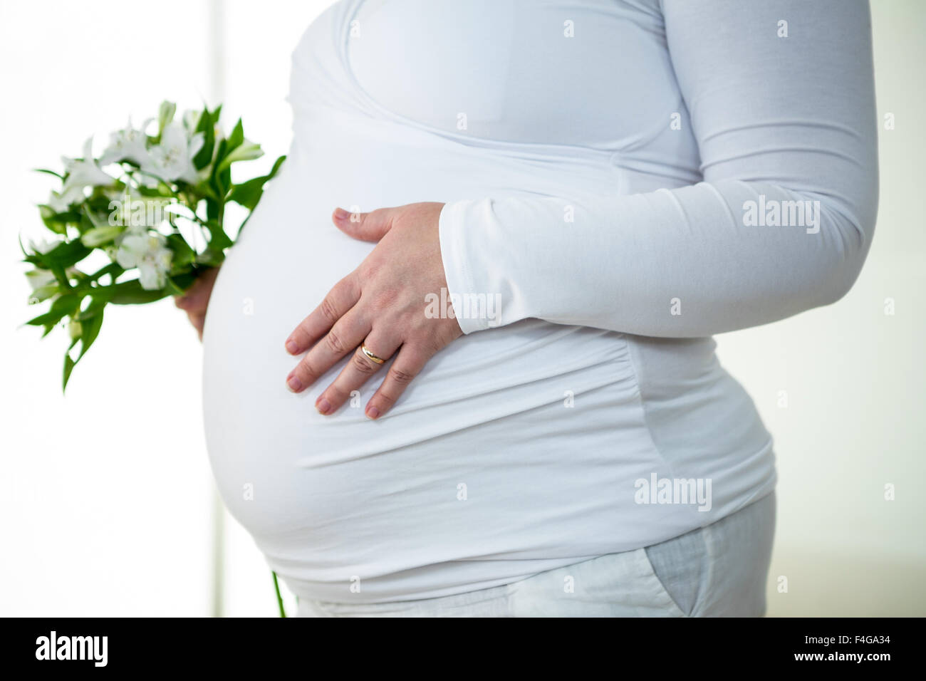Femme enceinte avec des fleurs de toucher son ventre Banque D'Images
