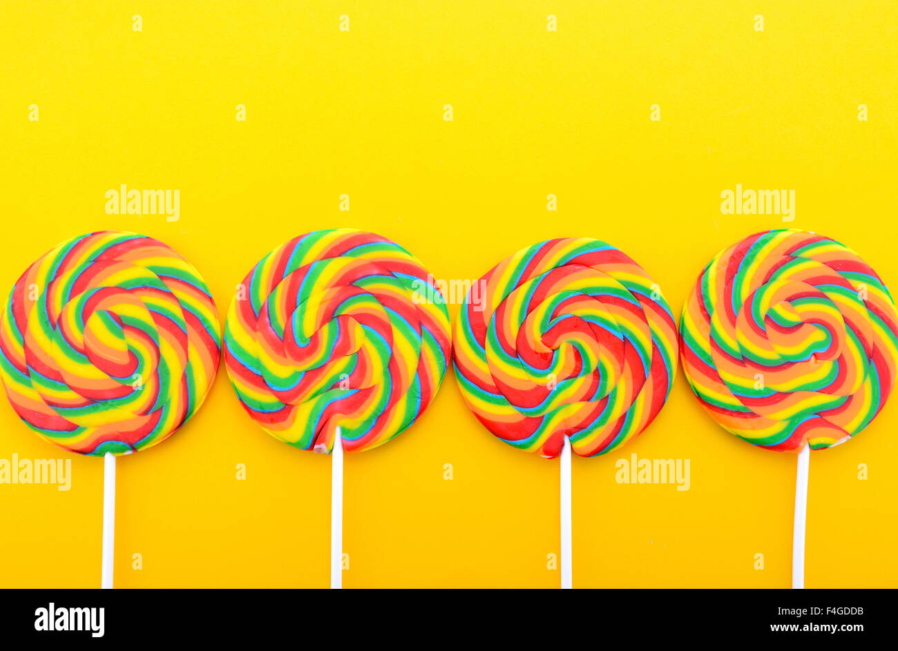 Arc-en-ciel lumineux lollipop candy sur table en bois jaune coloré pour Halloween Trick ou traiter ou aire de travail. Banque D'Images