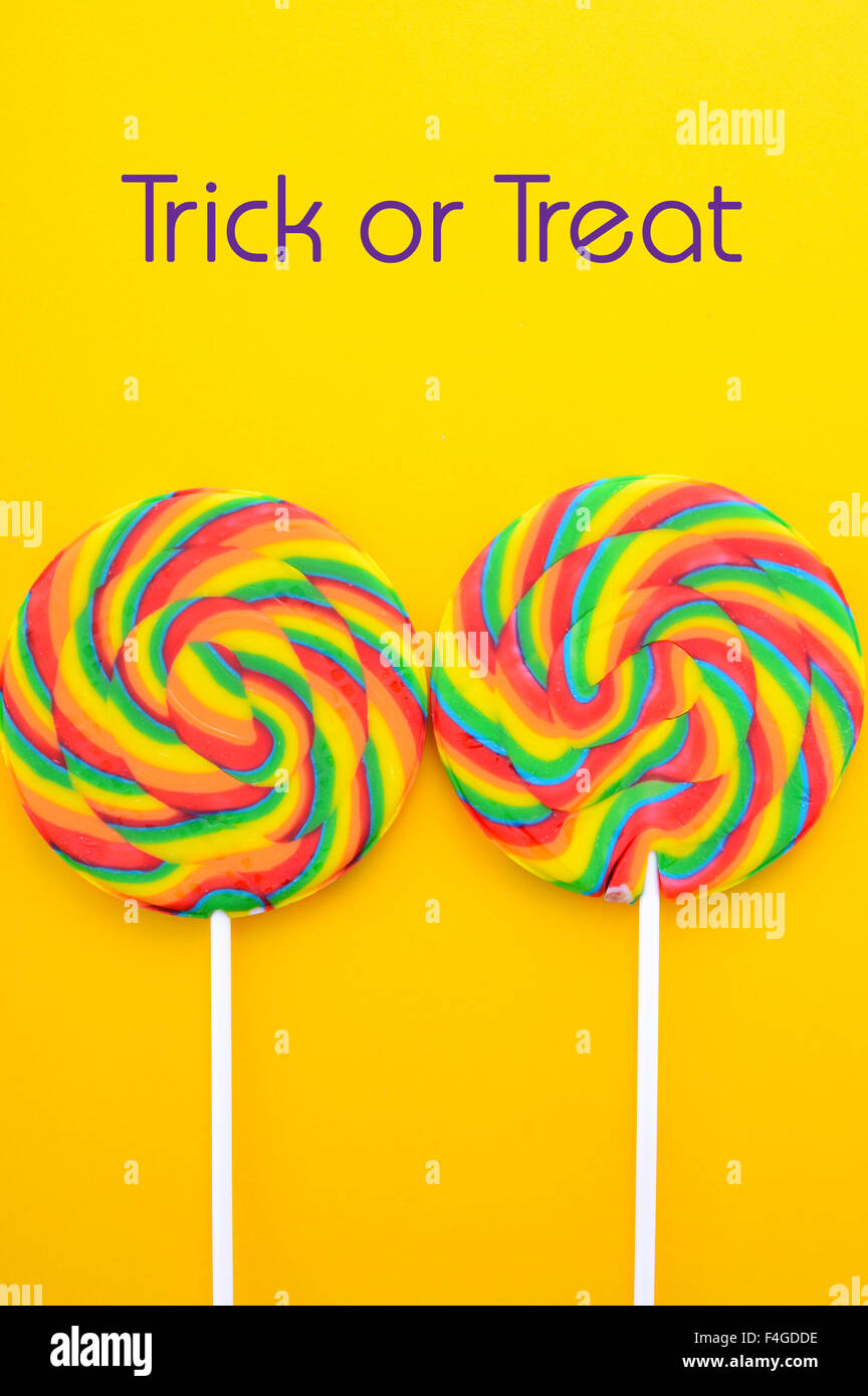 Arc-en-ciel lumineux lollipop candy sur table en bois jaune coloré pour Halloween Trick ou traiter ou aire de travail. Banque D'Images