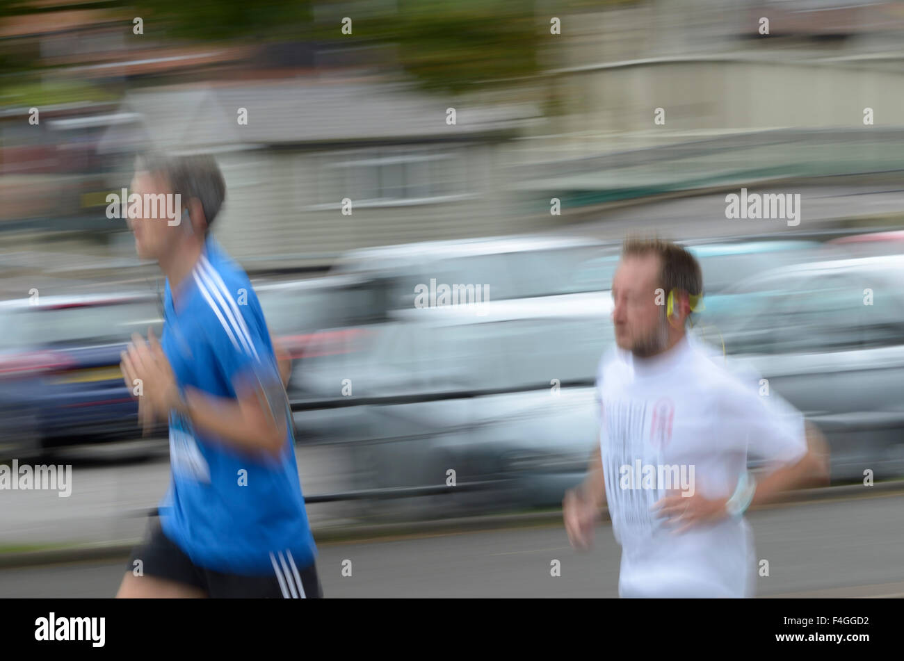 Coureurs dans une course avec des voitures et intentionnelles flou de vitesse Banque D'Images