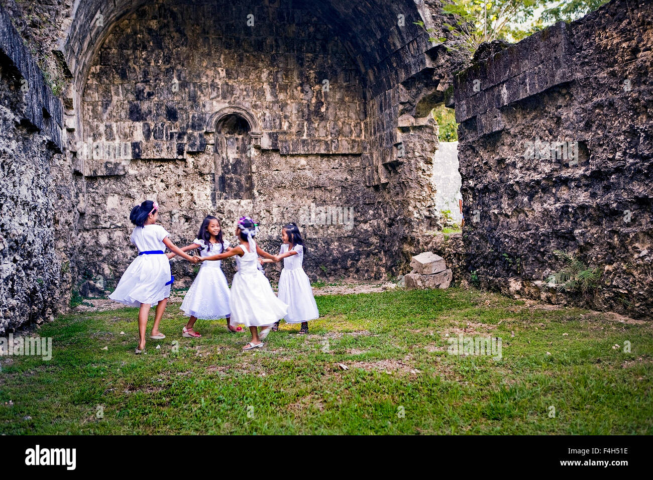 Quatre femmes enfants philippins en danse ancienne église ruines dans les Philippines. Banque D'Images