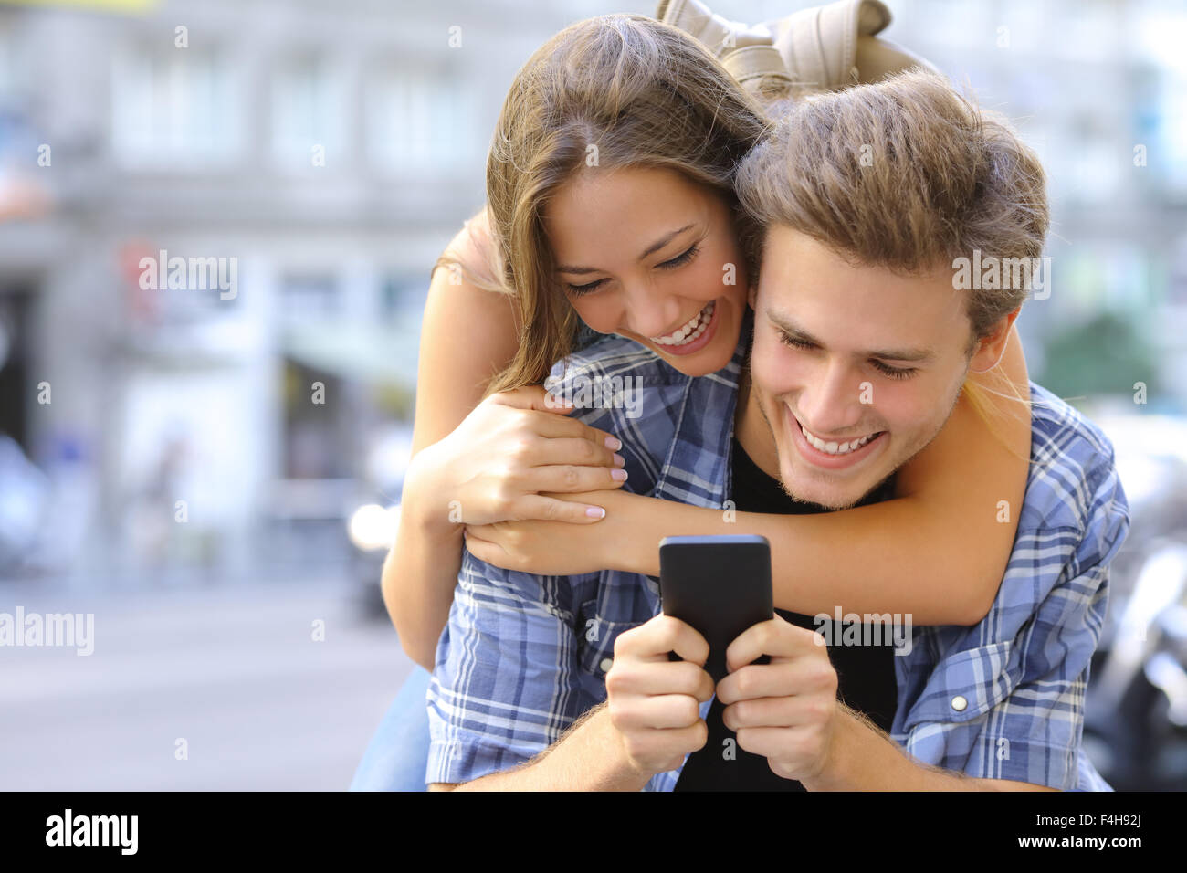 Couple ou entre amis rire drôle et amusant avec un téléphone intelligent dans une grande ville street Banque D'Images