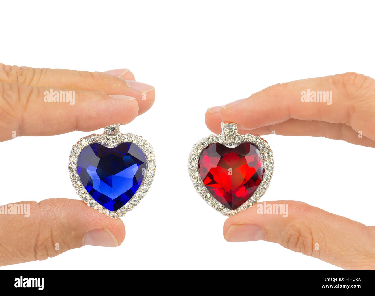 Les doigts de l'homme et de la femme tenant bijoux bleu et rouge coeur isolé sur fond blanc Banque D'Images
