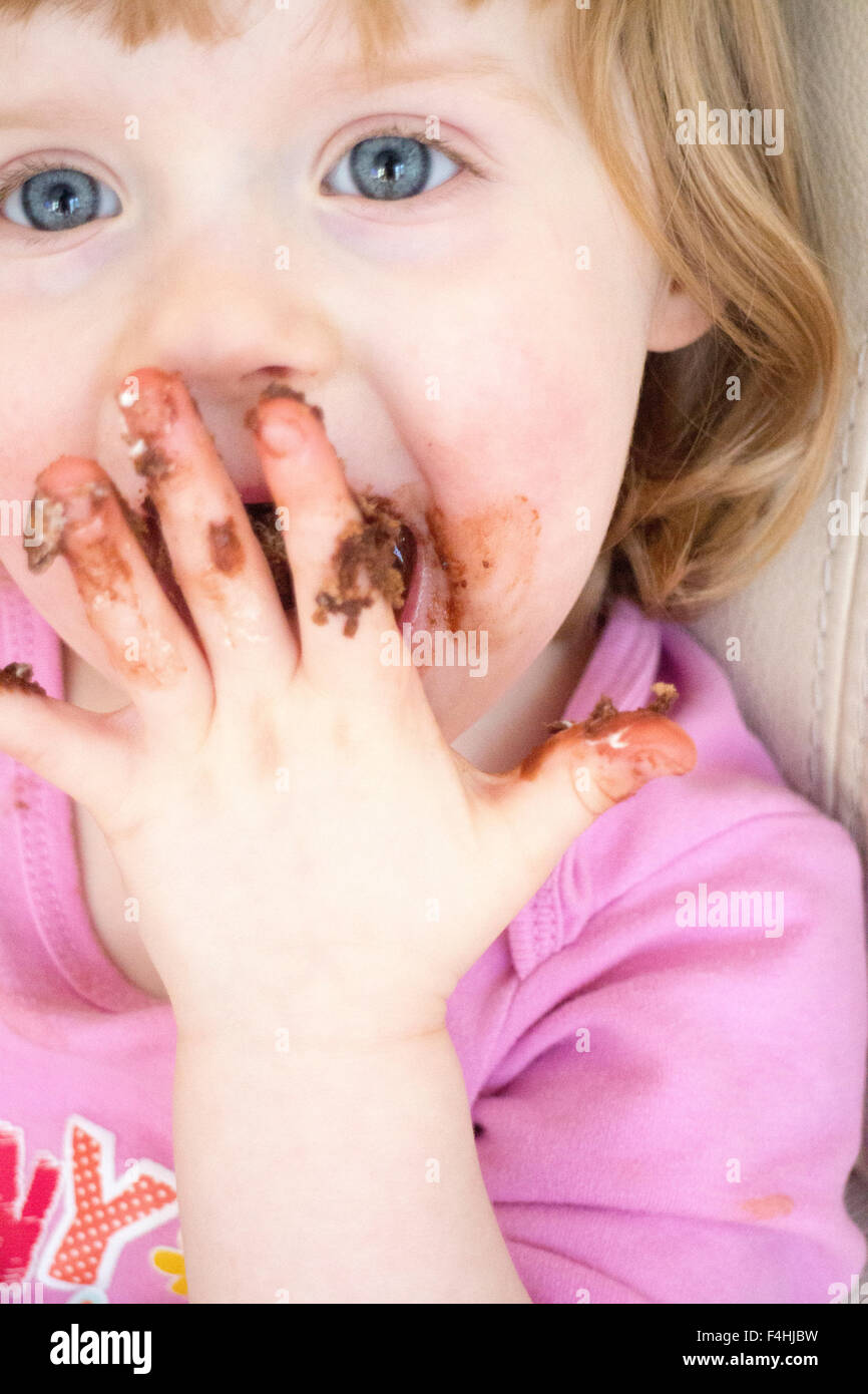 Quatre ans, fille avec du chocolat sur les mains et le visage Banque D'Images