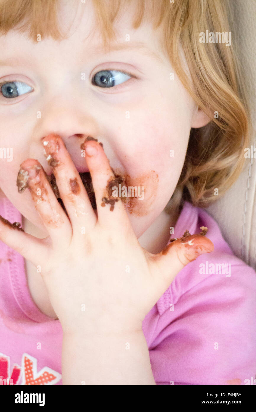 Quatre ans, fille avec du chocolat sur les mains et le visage Banque D'Images