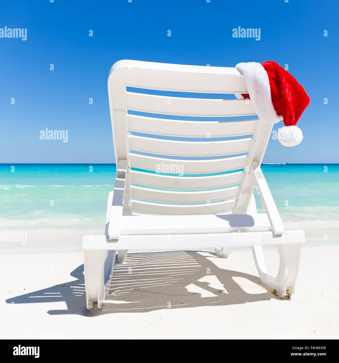Santa Claus Hat sur les transats près de tropical calme plage avec de l'eau de la mer turquoise des Caraïbes et du sable blanc. Vacances de Noël concep Banque D'Images