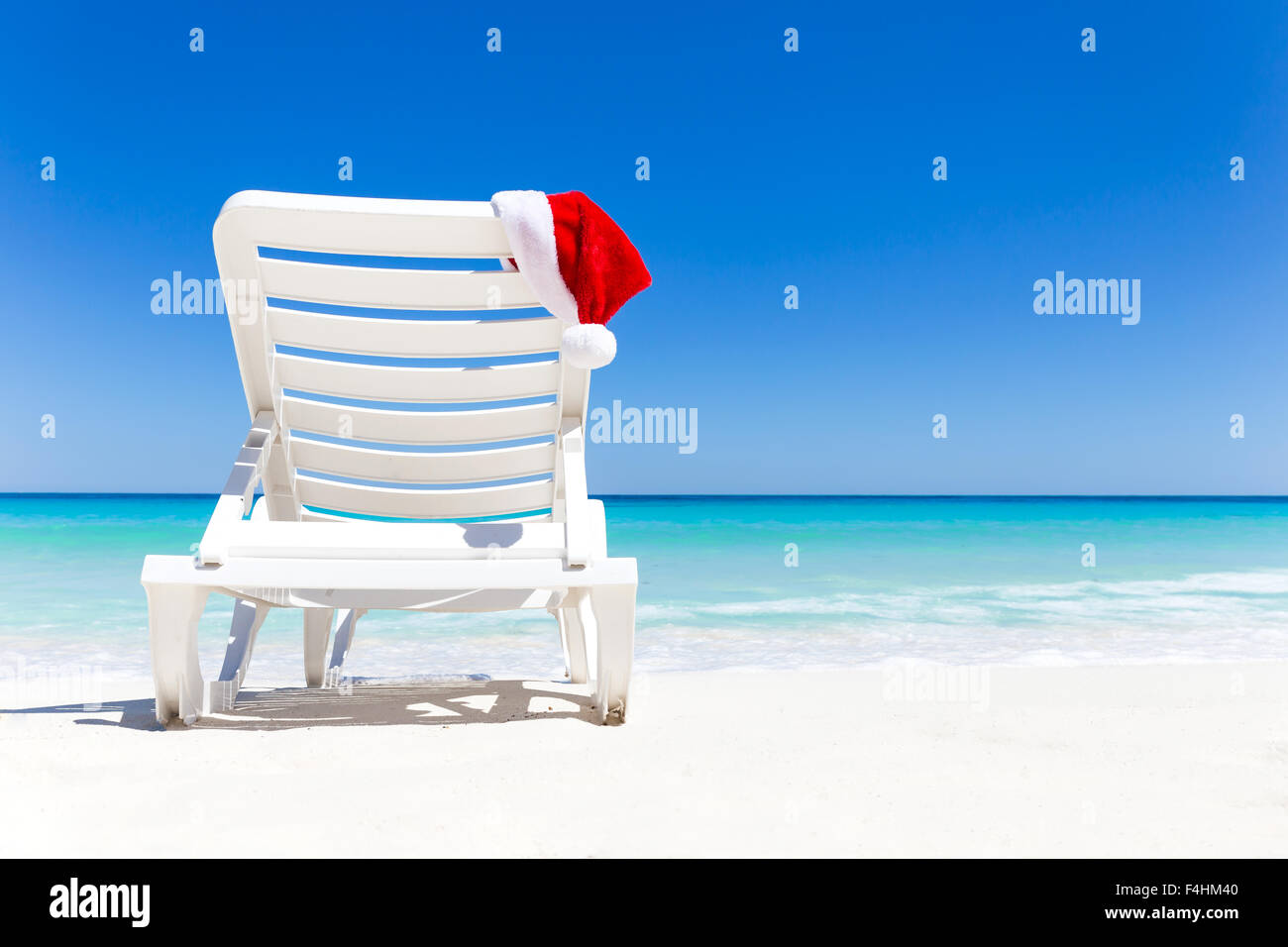 Santa Claus Hat sur les transats près de tropical calme plage avec de l'eau de la mer turquoise des Caraïbes et du sable blanc. Vacances de Noël concep Banque D'Images