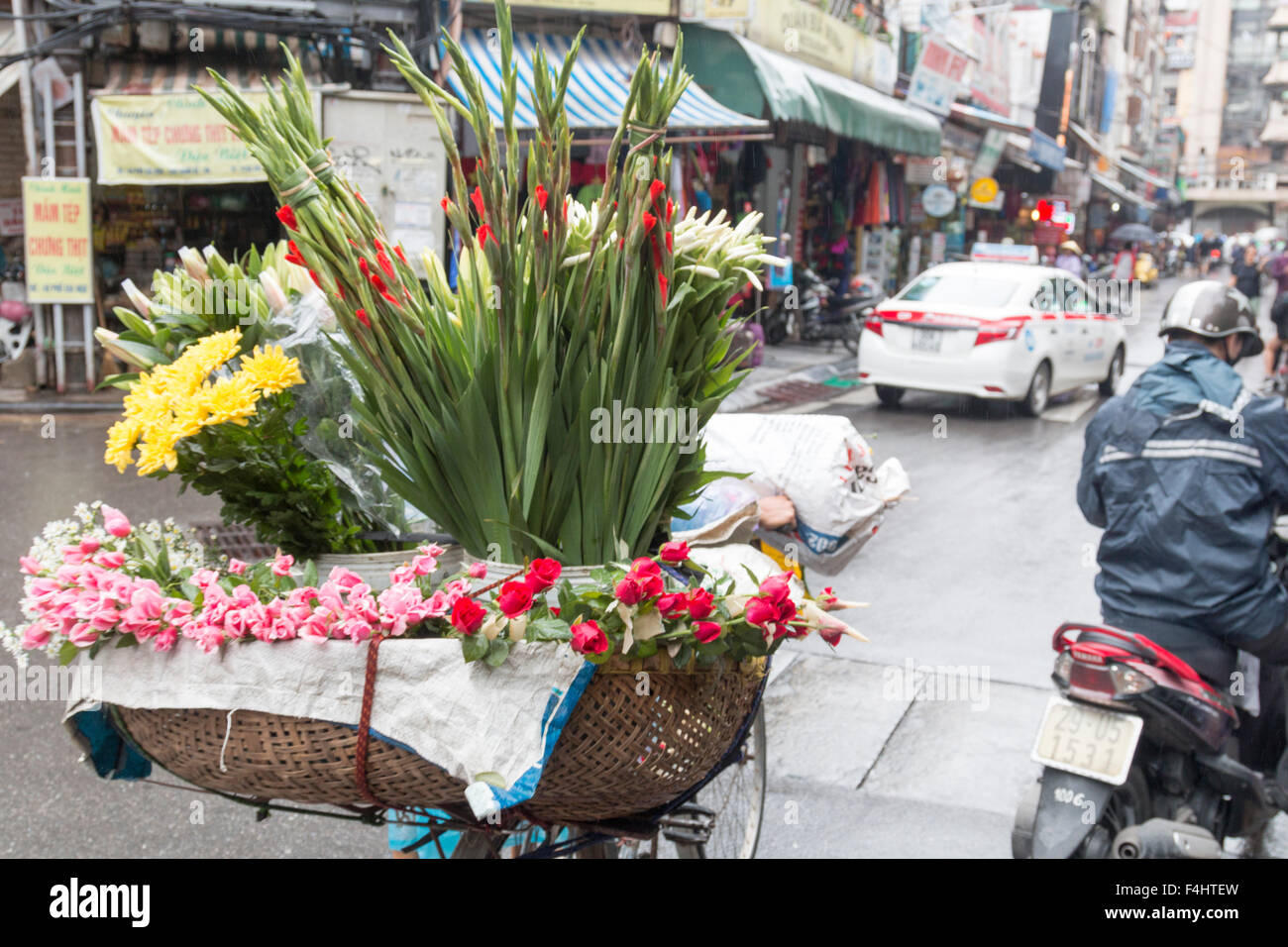 Dame vietnamienne vendant des fleurs dans le vieux quartier de Hanoi du panier sur son vélo, Vietnam, Asie Banque D'Images