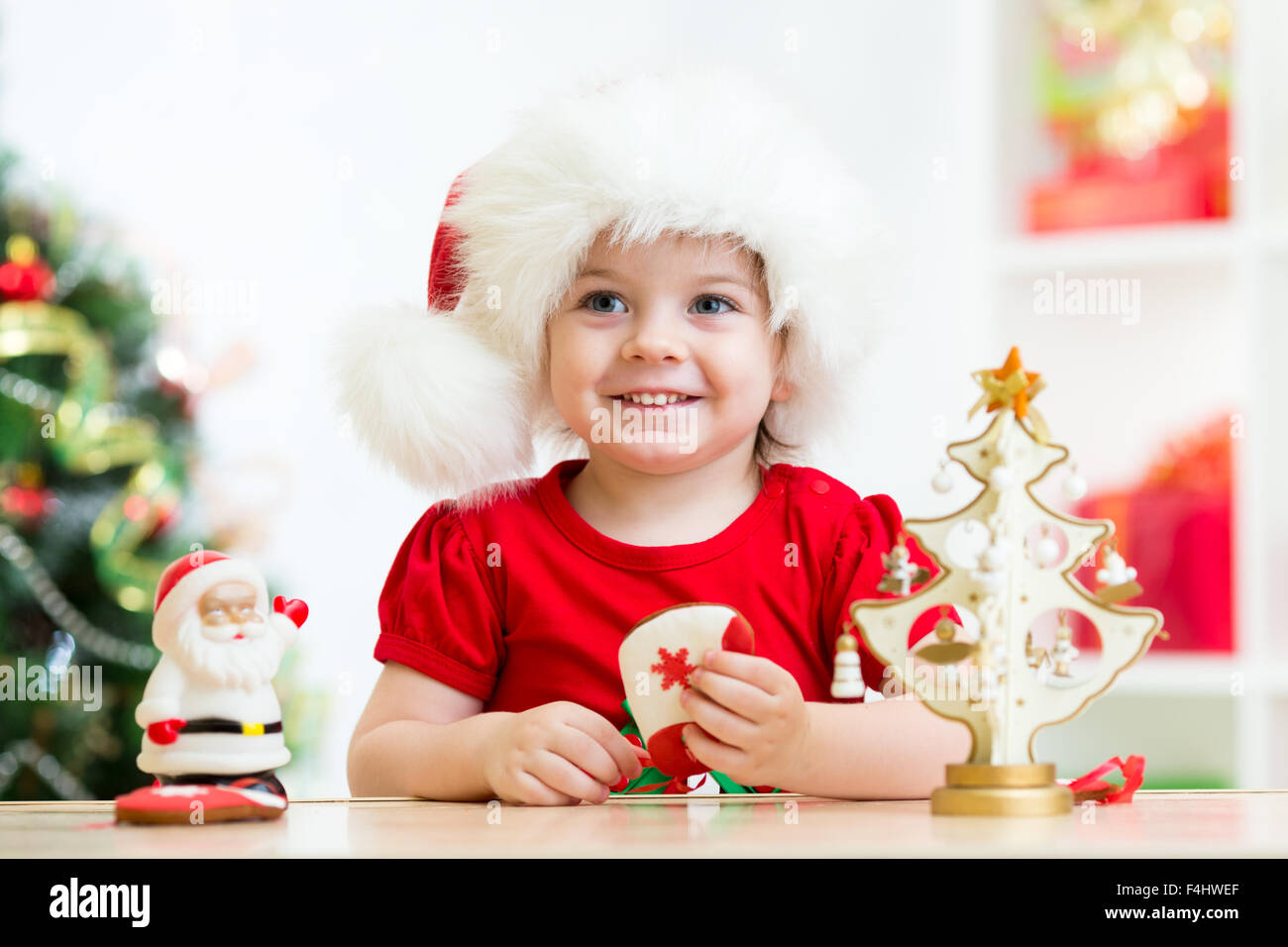 Petite fille enfant portant un chapeau de Père Noël rouge de fête avec des biscuits de Noël Banque D'Images