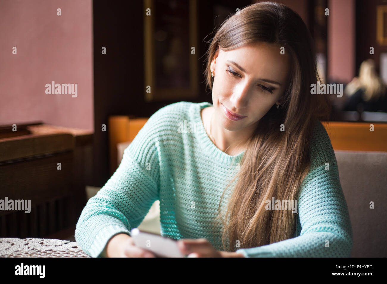 Portrait de la belle jeune femme aux longs cheveux noirs à l'aide de son téléphone portable dans le café. Banque D'Images