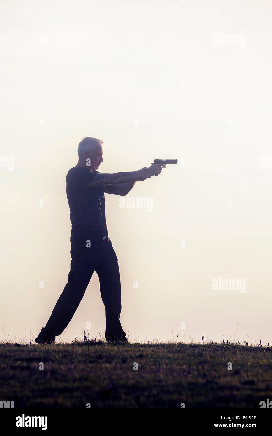 Silhouette d'un homme avec une arme à feu Banque D'Images