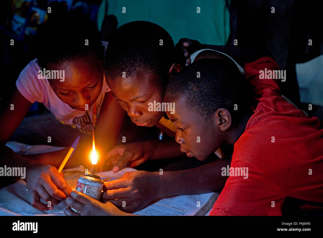 Les enfants africains d'essayer de lire livre avec lumière kérosène Kamere Lake Naivasha au Kenya Banque D'Images