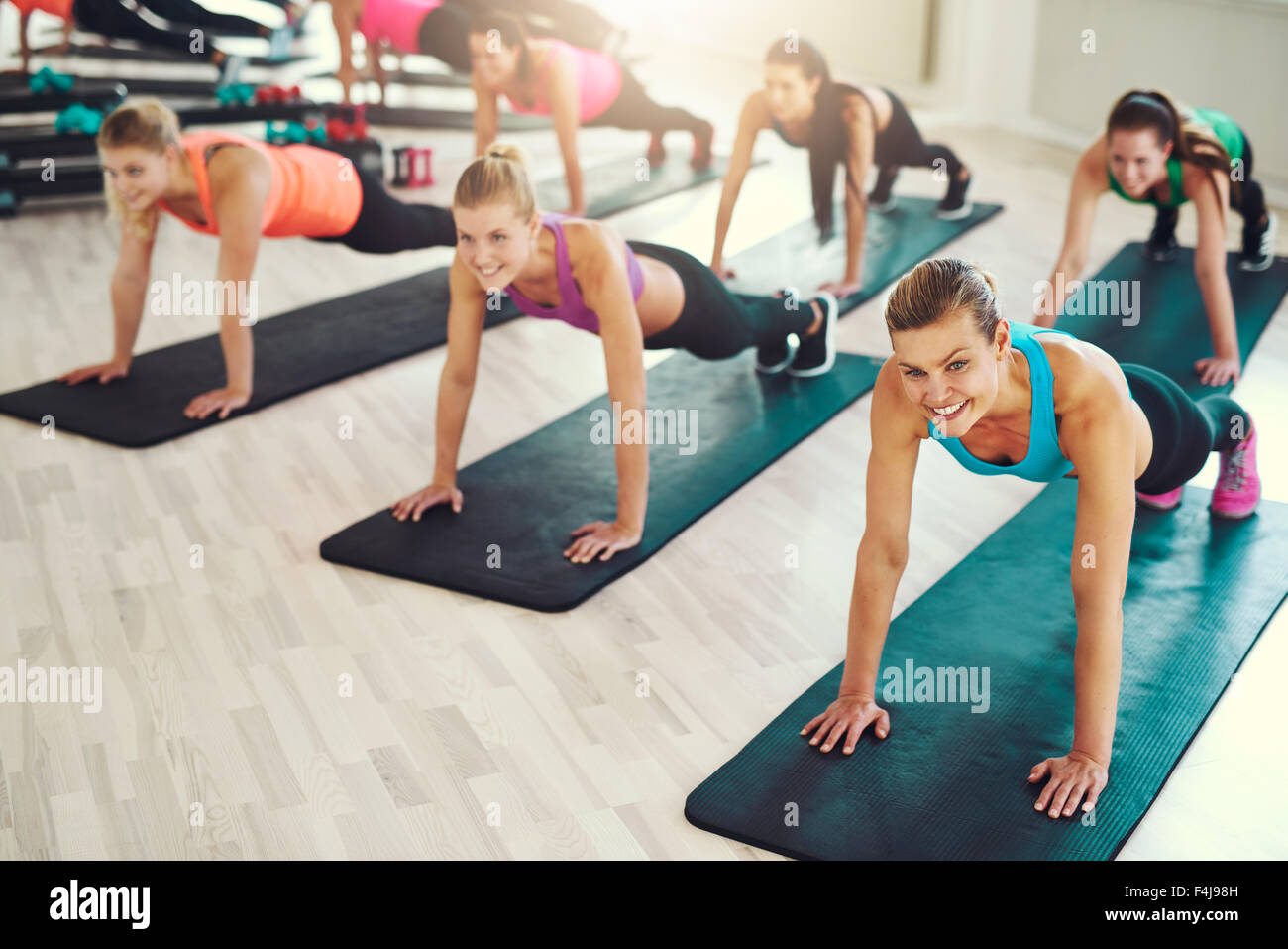Grand groupe de jeunes femmes travaillant dans une salle de sport faire poussez se lève dans une classe d'aérobic dans un concept de santé et de remise en forme Banque D'Images