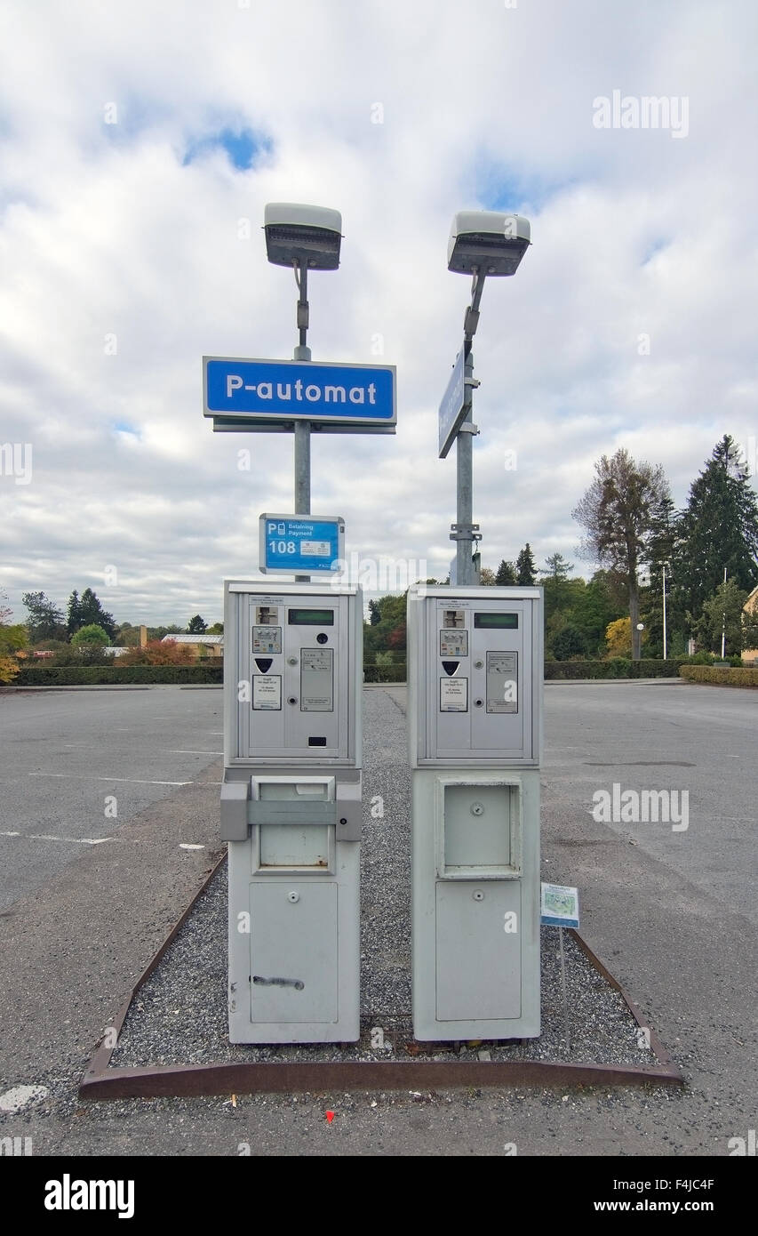 Un parcomètre dans un parking vide sur un jour nuageux Banque D'Images