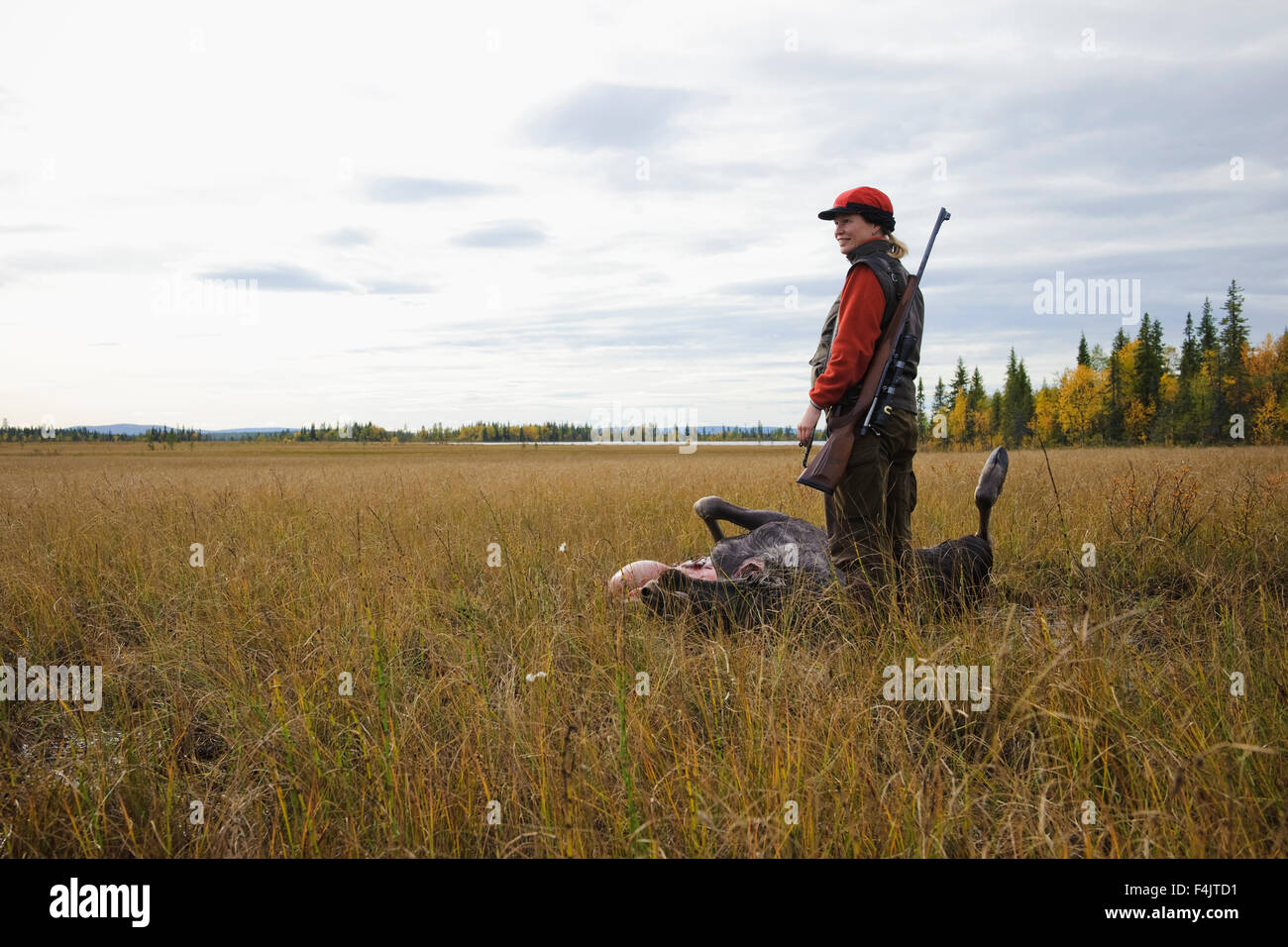 Femme avec carabine debout à côté de corps mort de red deer dans swamp Banque D'Images