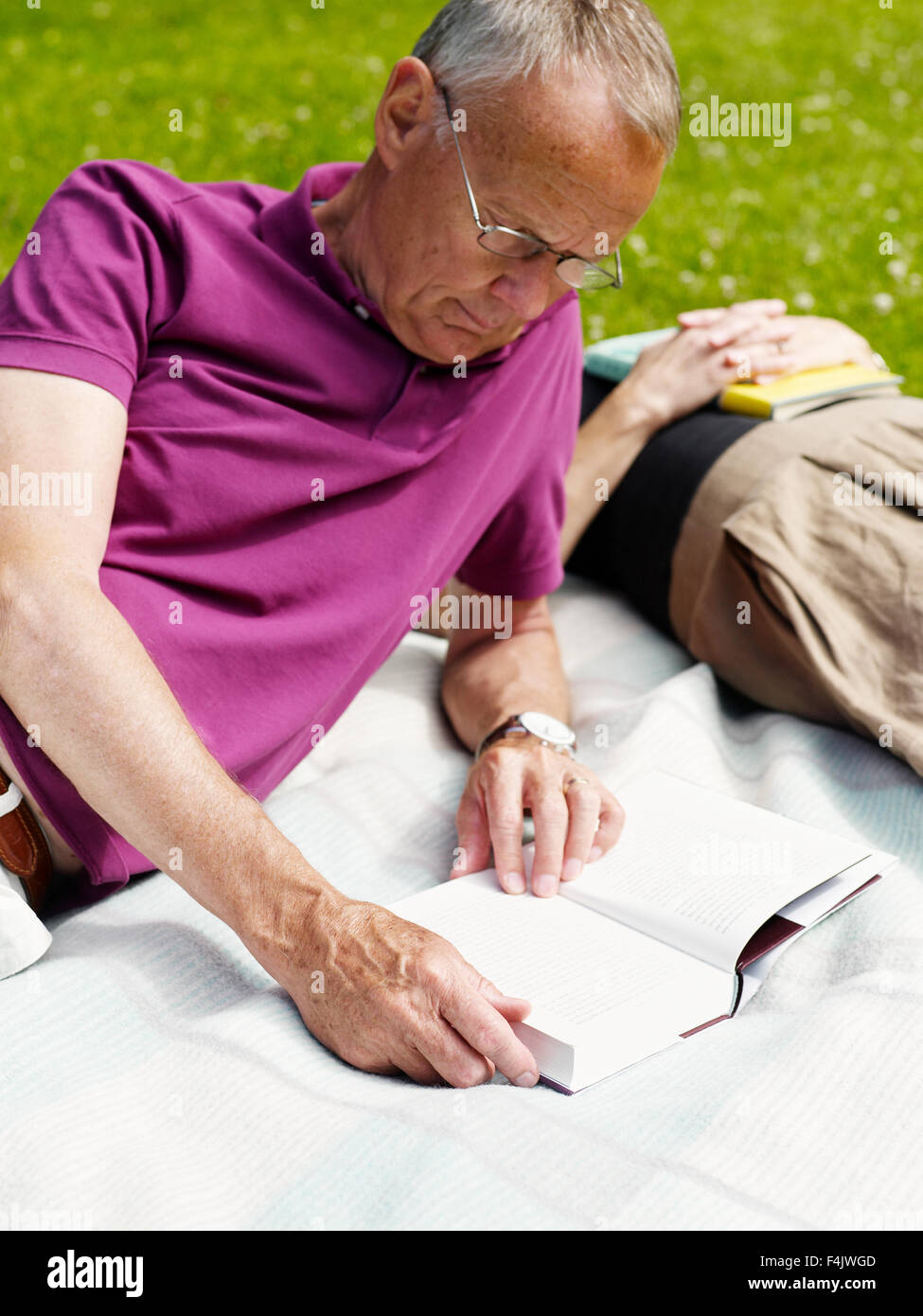 Man lying on blanket and reading book Banque D'Images