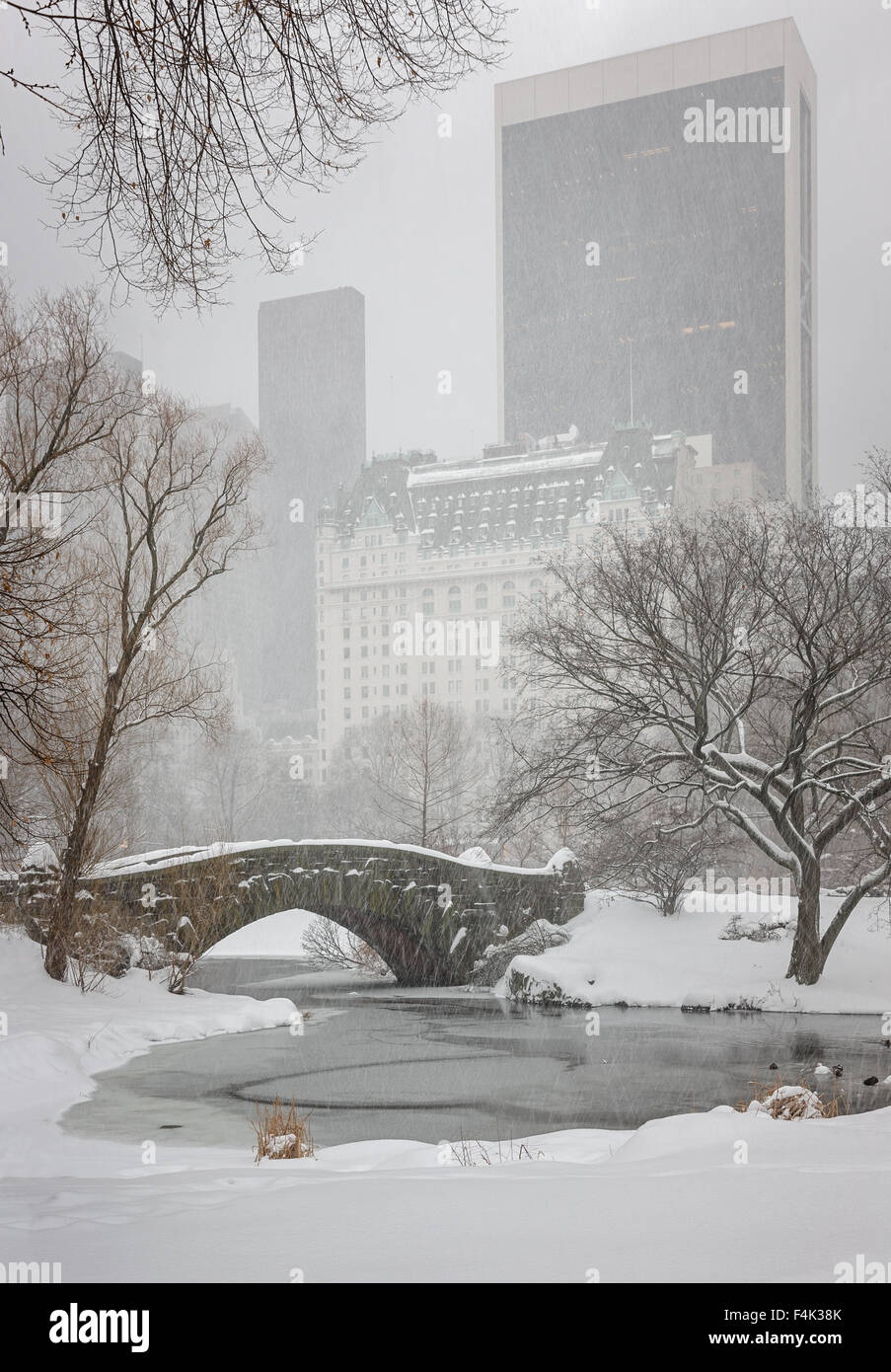 Neige sur Central Park's Gapstow Bridge et l'étang . Scène d'hiver tranquille, avec une vue sur les gratte-ciel de Manhattan, New York Banque D'Images