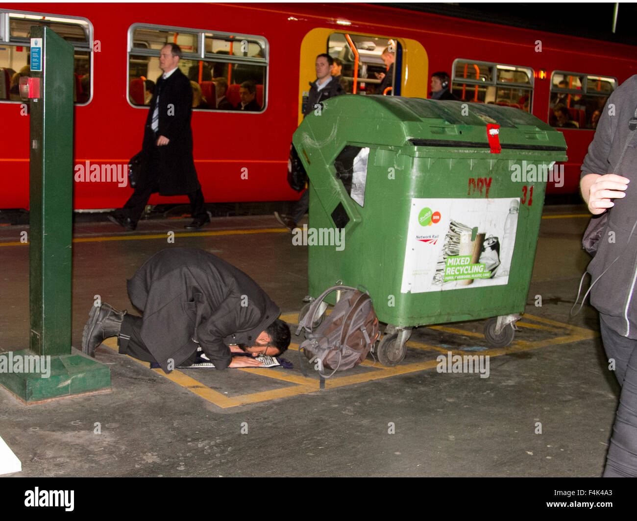 Londres, Royaume-Uni. 19 octobre 2015. Un homme effectue une prière islamique à côté d'un bac de recyclage sur une plate-forme du train à la gare de Waterloo London Crédit : amer ghazzal/Alamy Live News Banque D'Images